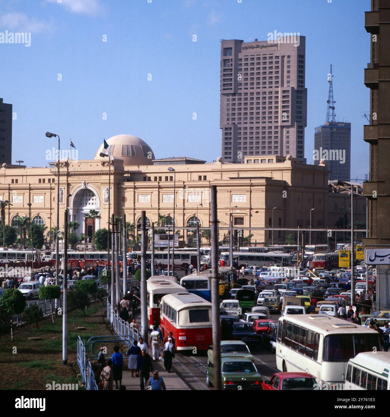 Tägliches Verkehrschaos auf der Meret Basha Straße mit Blick auf das Ägyptische Museum (Kuppel) und den Ramses Hotelturm in Kairo, nahe vom Midan al Tahrir Platz, Ägypten um 1987. Banque D'Images