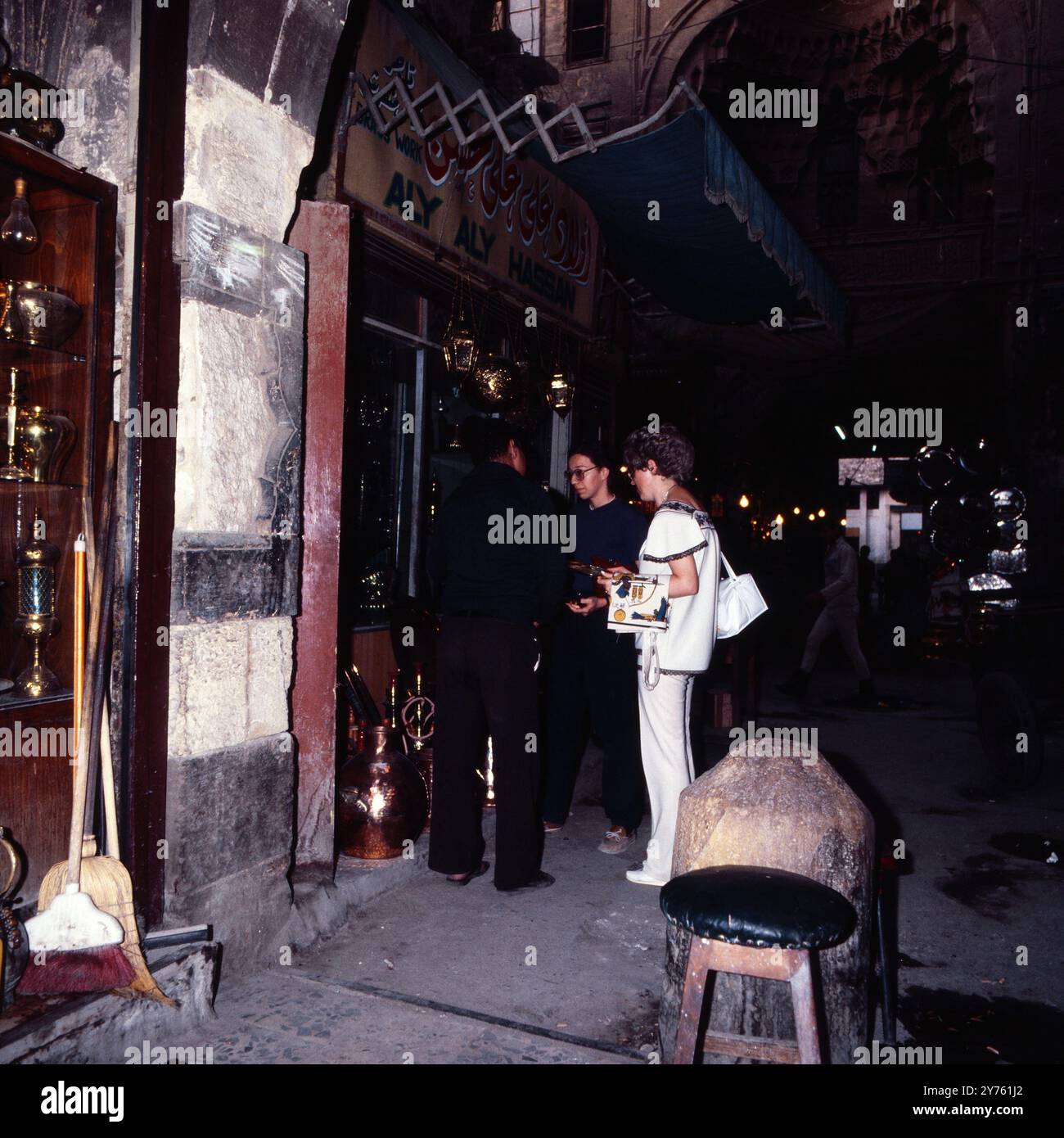 Touristen bewundern die große Auswahl an kunsthandwerklich bearbeitetem Kupfer in einem Geschäft im Chan el Chalili Basar in Kairo, Ägypten um 1987. Banque D'Images