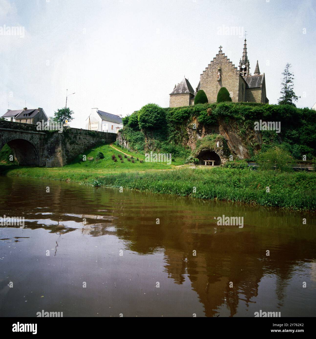 Kleine gotische Kirche an einer Steinbogenbrücke über den Fluss Oust in der Gemeinde Val d'Oust in der Bretagne, Frankreich um 1984. Banque D'Images