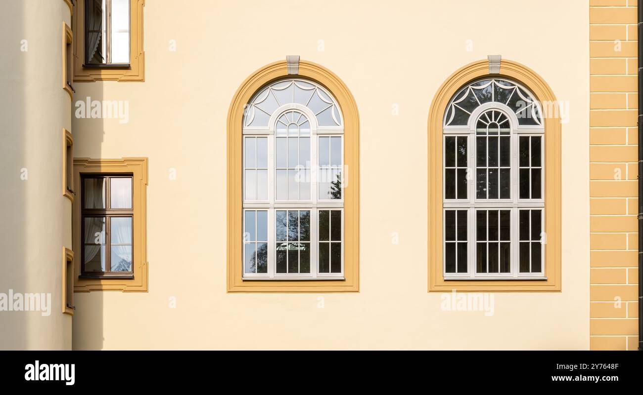 Façade de bâtiment classique élégante avec fenêtres cintrées symétriques, mur jaune ensoleillé et détails architecturaux décoratifs mettant en valeur l'Europea vintage Banque D'Images