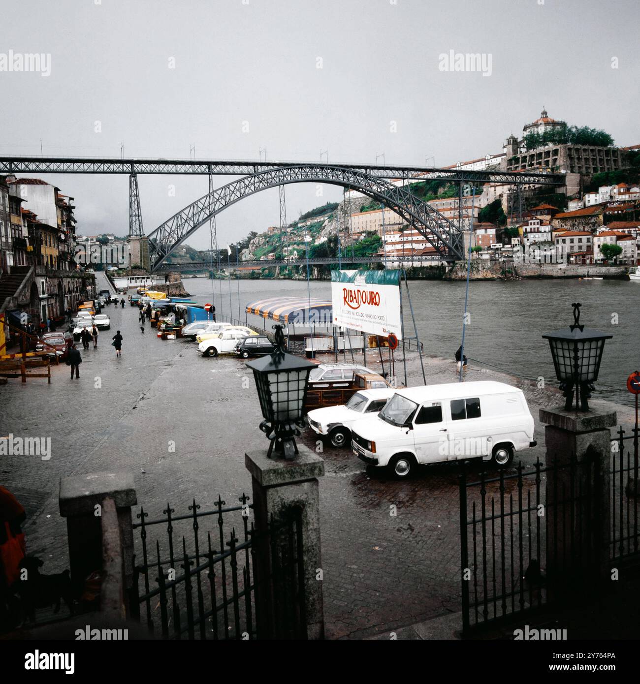 Autos parken im Hafenareal vor der Ponte Dom Luis I in Porto in der Region Norte, Portugal um 1981. Banque D'Images