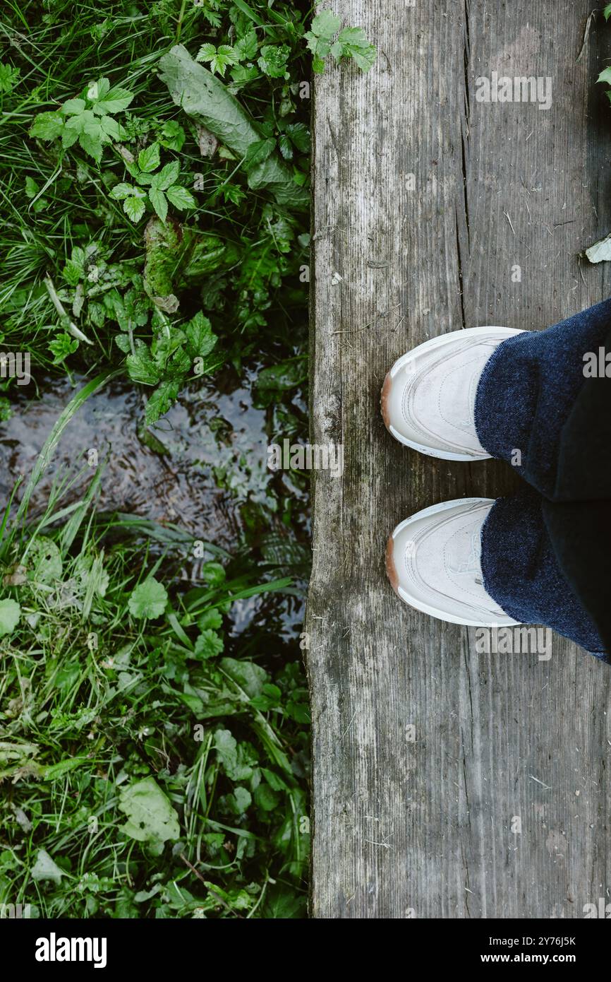 Femme en baskets blanches est debout dans la forêt. Banque D'Images Femme en baskets blanches est debout dans la forêt. Banque D'Images