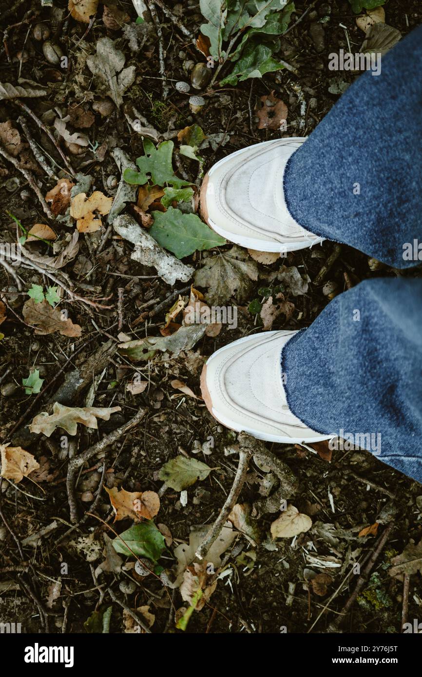 Femme en baskets blanches est debout dans la forêt. Banque D'Images Femme en baskets blanches est debout dans la forêt. Banque D'Images