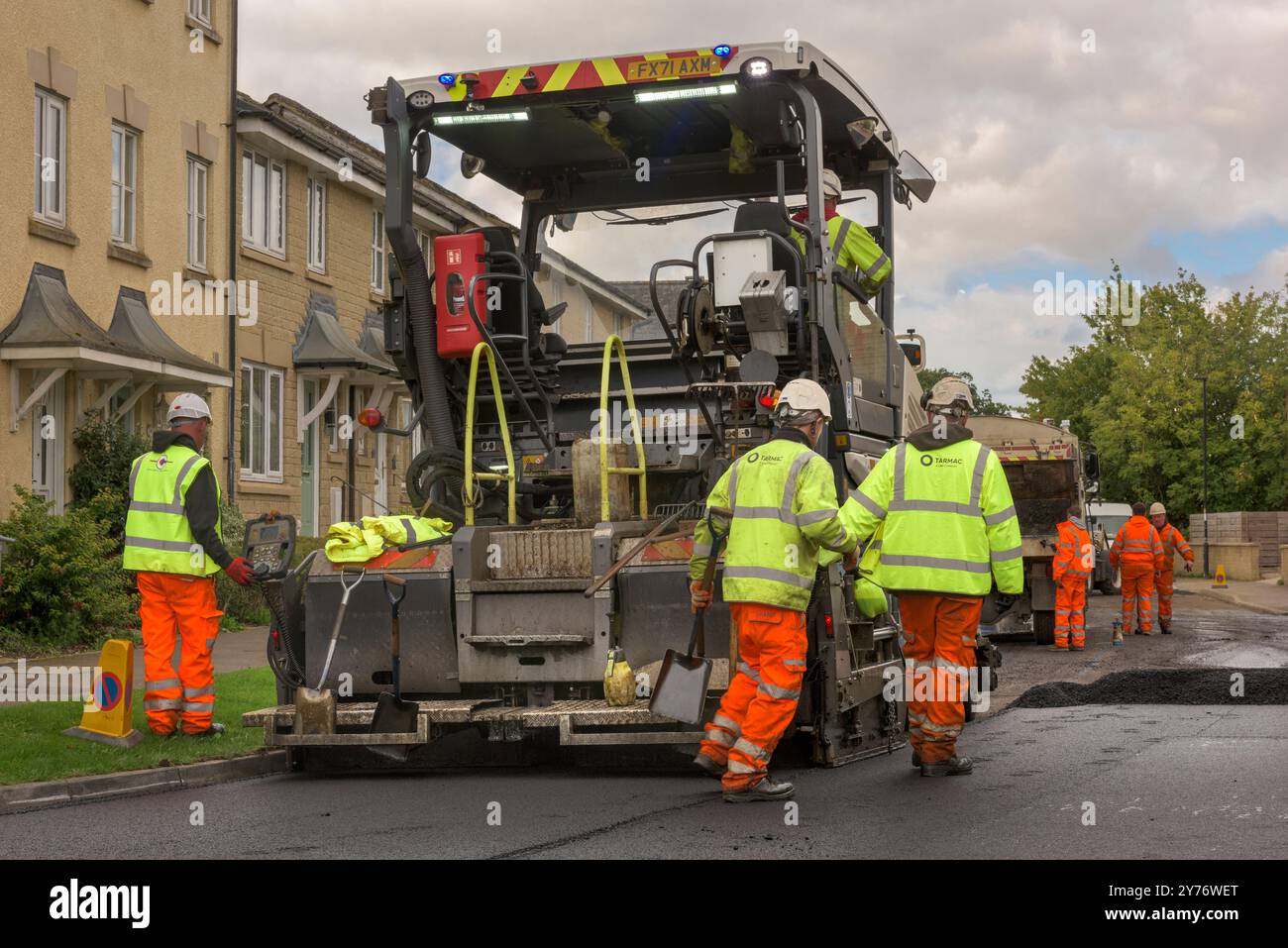 Une équipe d'ouvriers opérant de la machinerie lourde pour resurfaçer une route résidentielle dans le Wiltshire. Banque D'Images