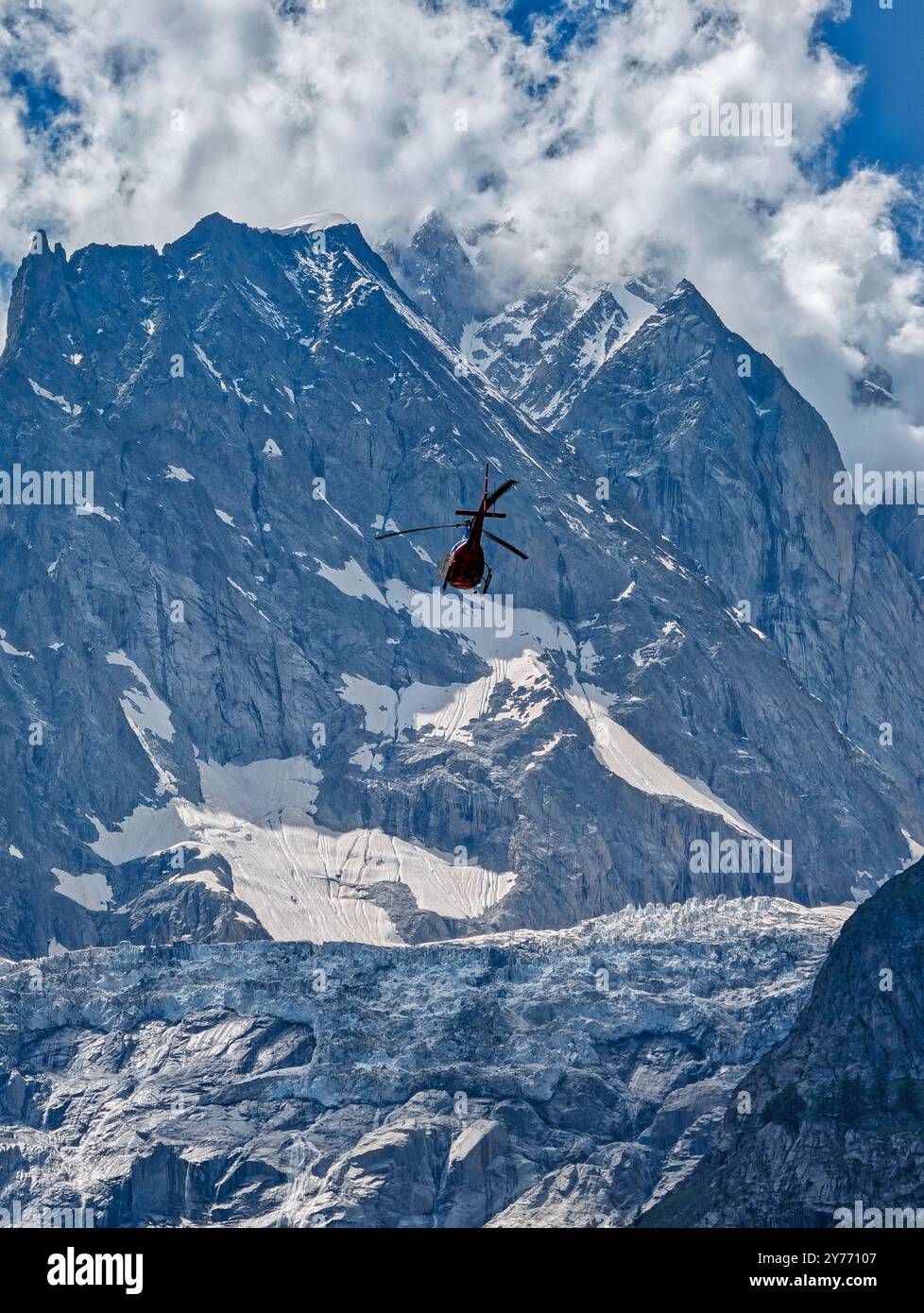 un hélicoptère décolle pour une mission de sauvetage contre l'imposante toile de fond montagneuse des alpes Banque D'Images