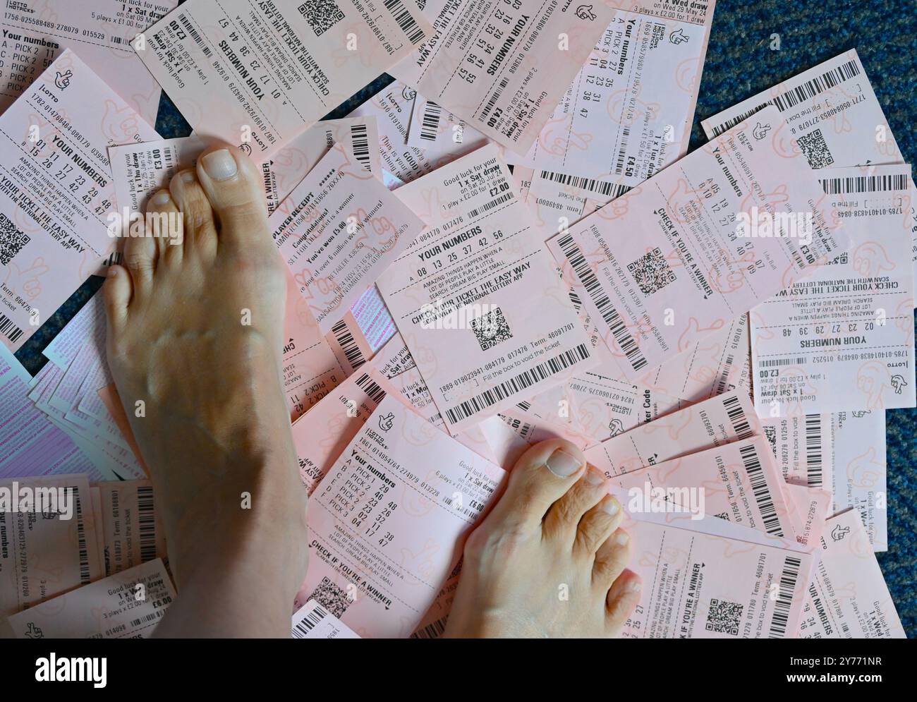 Pieds humains sur fond de billets de loterie. Banque D'Images