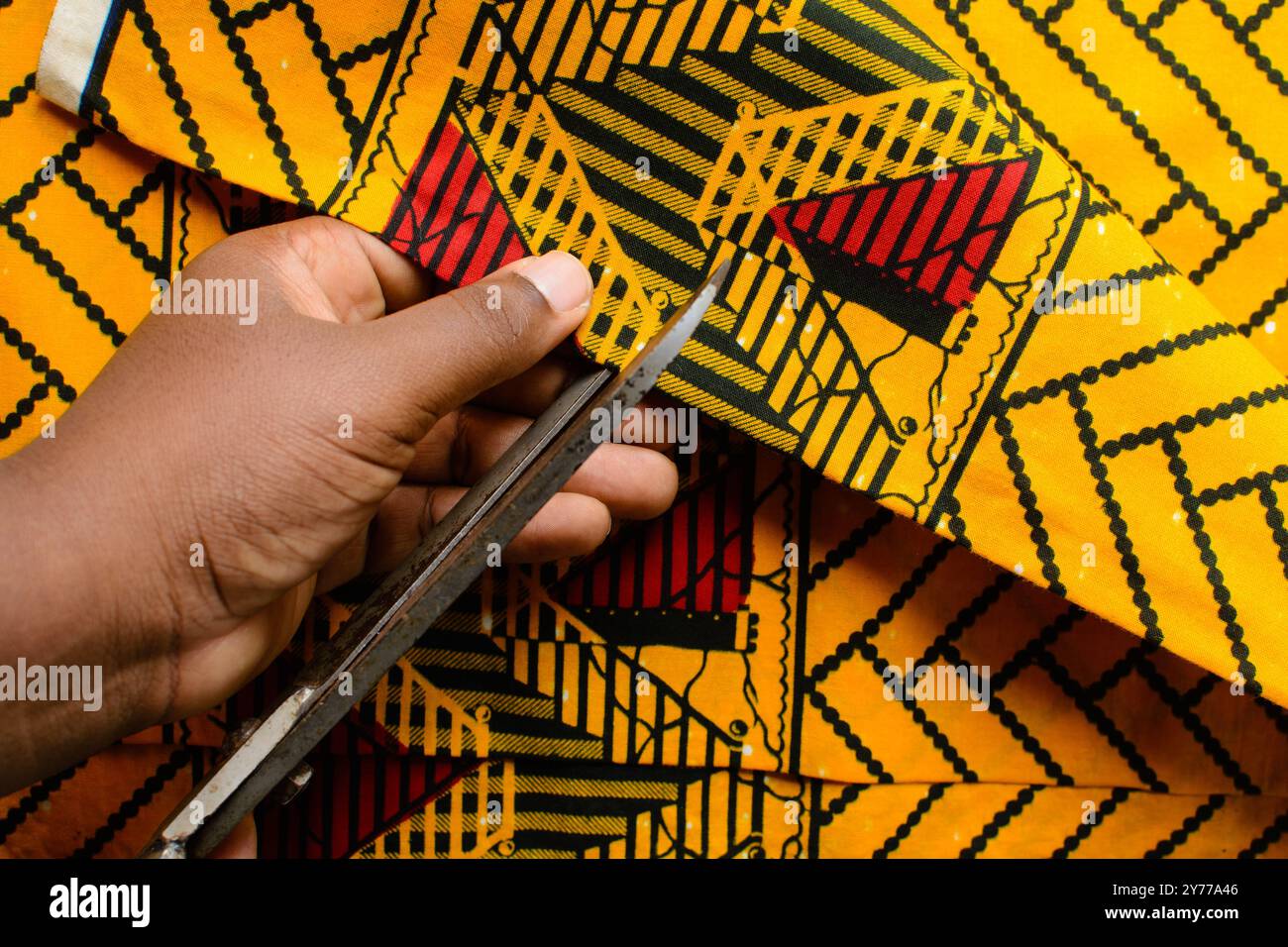 vue de dessus de couper le tissu ankara avec des ciseaux, flatlay de tissu de cire nigérian Banque D'Images