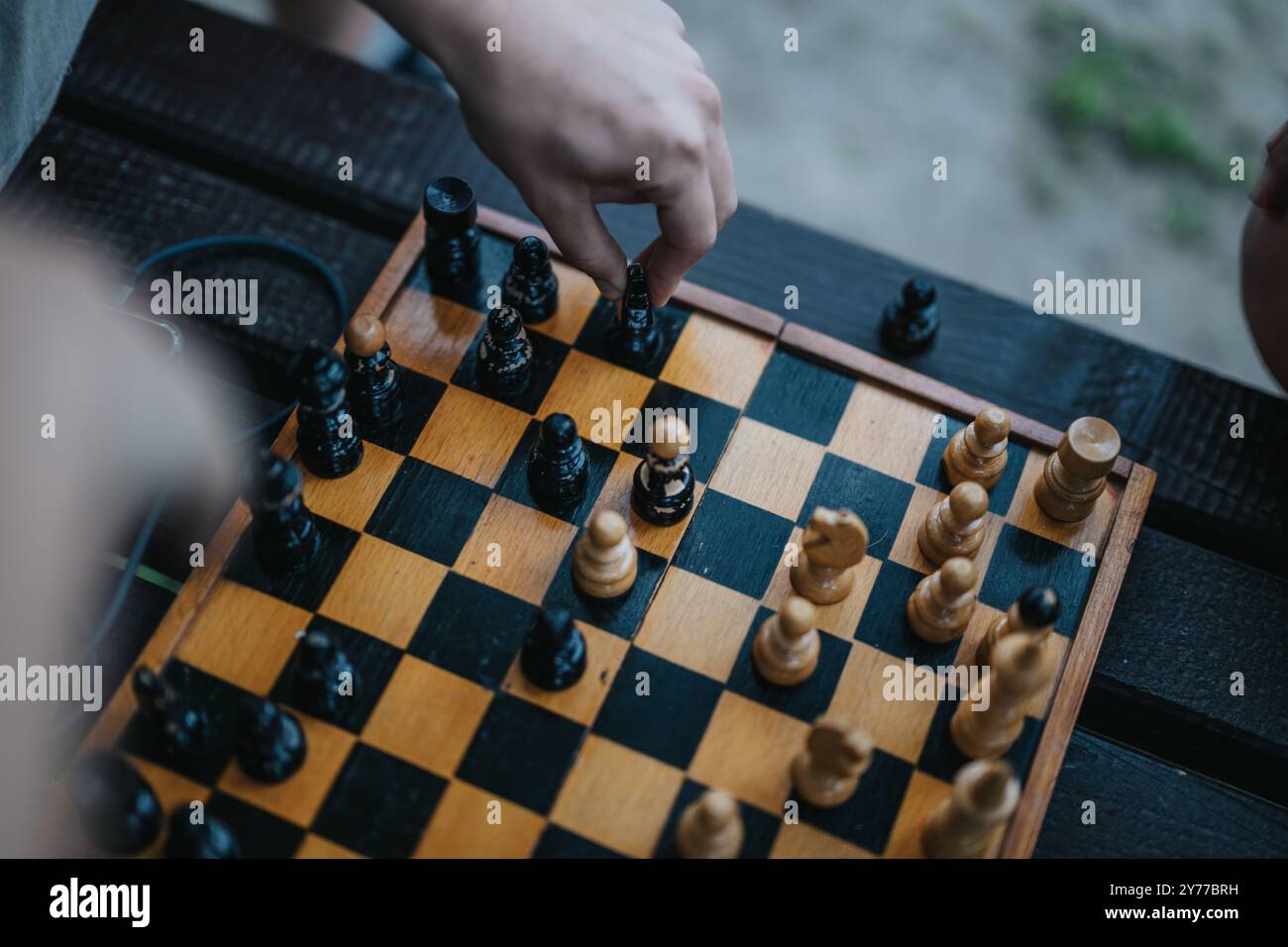 Mains déplaçant des pièces d'échecs sur un échiquier en bois extérieur Banque D'Images