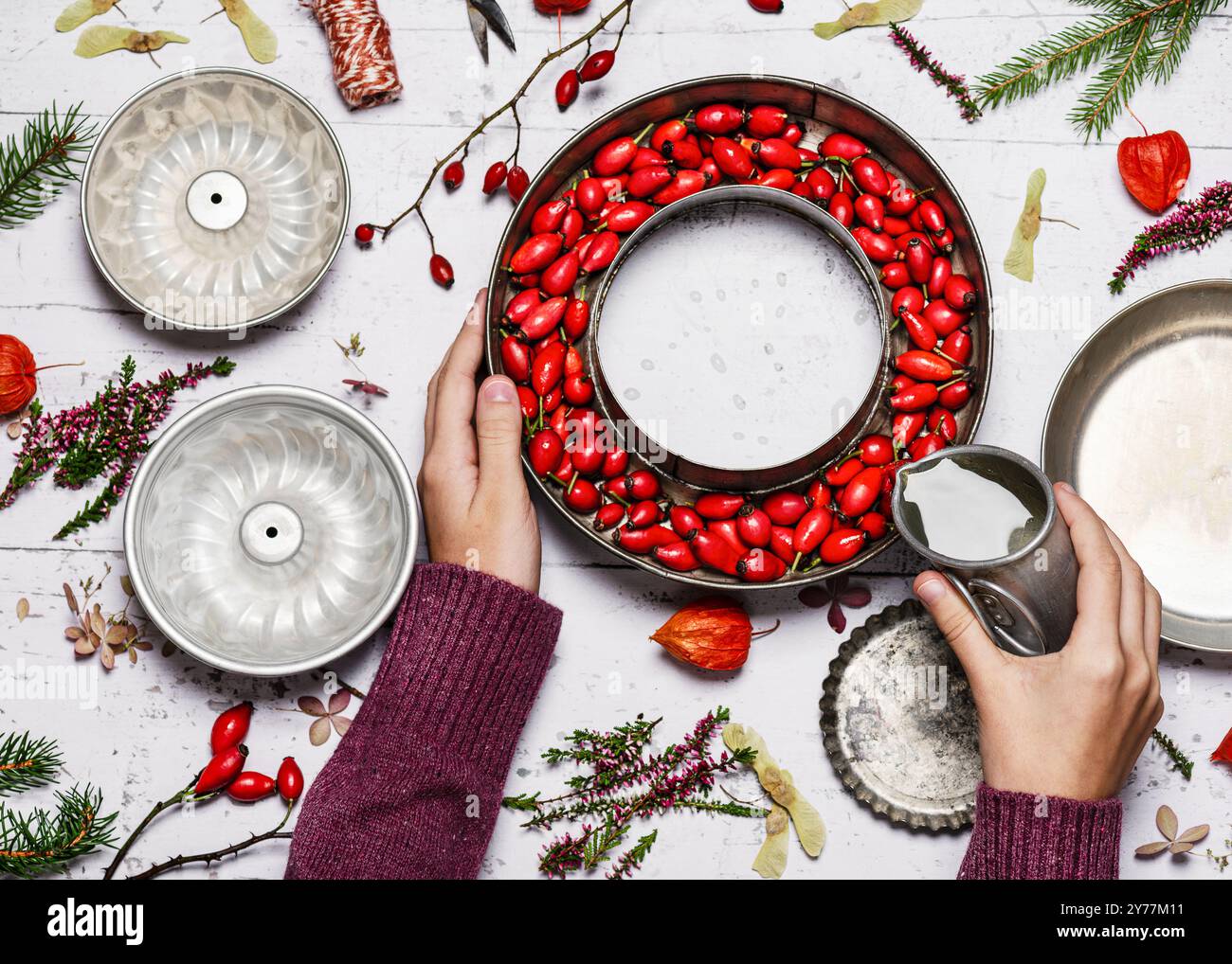 Étape 2. Enfant versant de l'eau dans la forme avec des hanches roses rouges pour créer une couronne de glace gelée. Concept de décoration d'hiver facile fait à la main. Banque D'Images