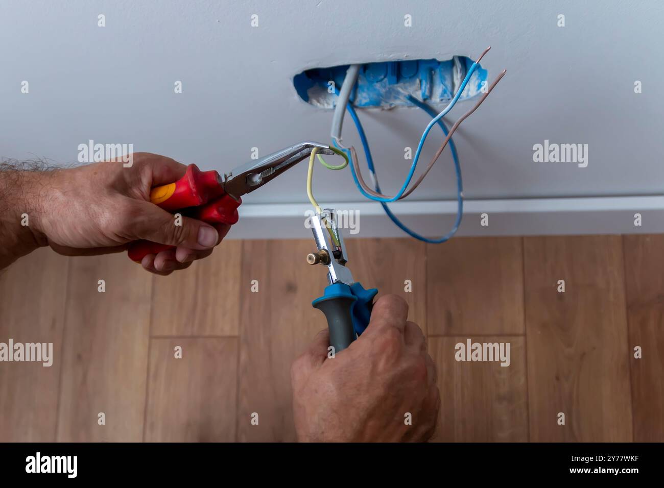 Électricien, examine la connexion du câble dans la ligne électrique. Le technicien tire le fil du conduit sur le chantier. Constructeur au travail, examine conne Banque D'Images