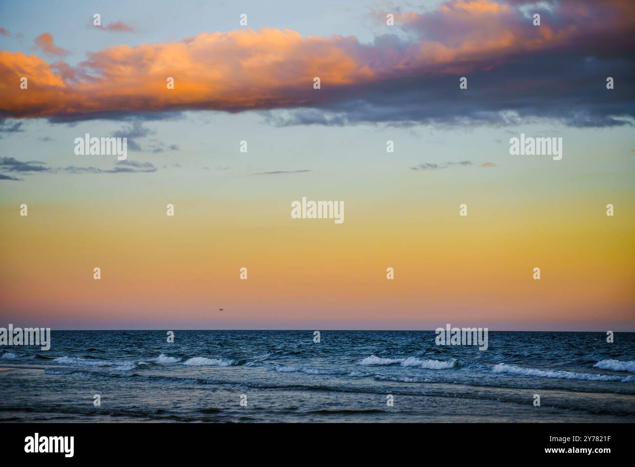 Beau ciel dégradé passant de l'orange au bleu au-dessus de la mer. Banque D'Images