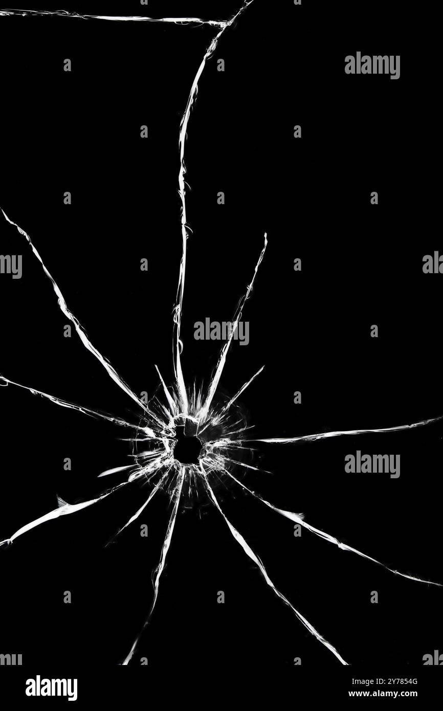 Trou d'un tir avec une arme dans le verre.Fissures à l'arrière de la voiture.Texture sur fond noir, effet du pare-brise cassé Banque D'Images