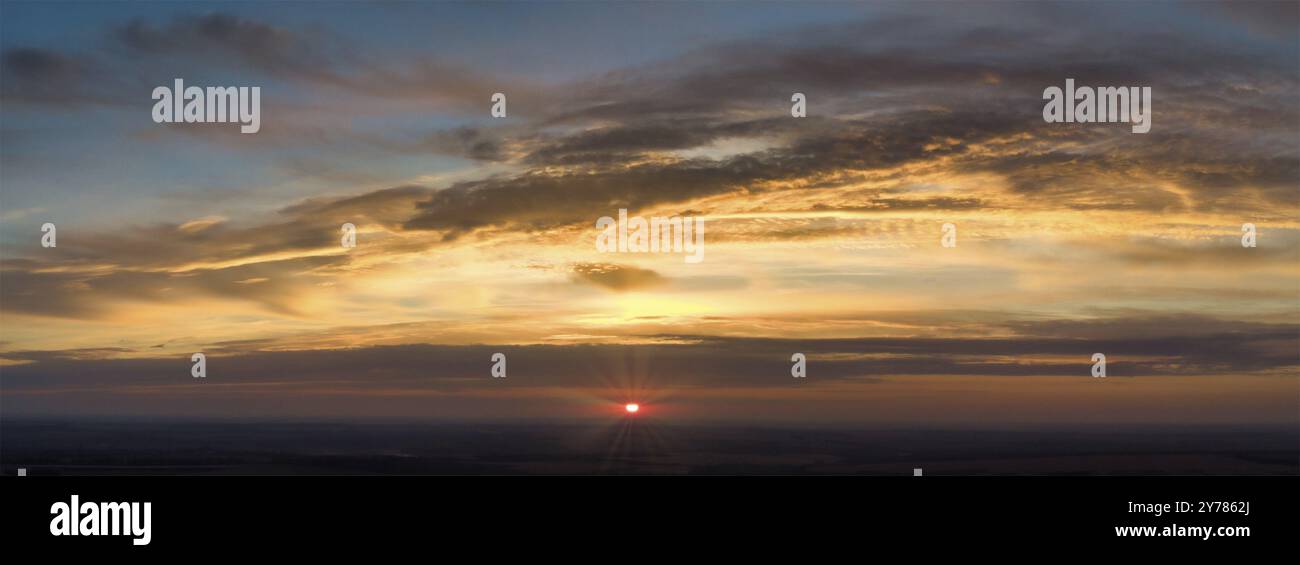 Panorama du lever du soleil avec les rayons rouges de l'arrière des nuages.Ciel flou et nuages orange abstraits Banque D'Images
