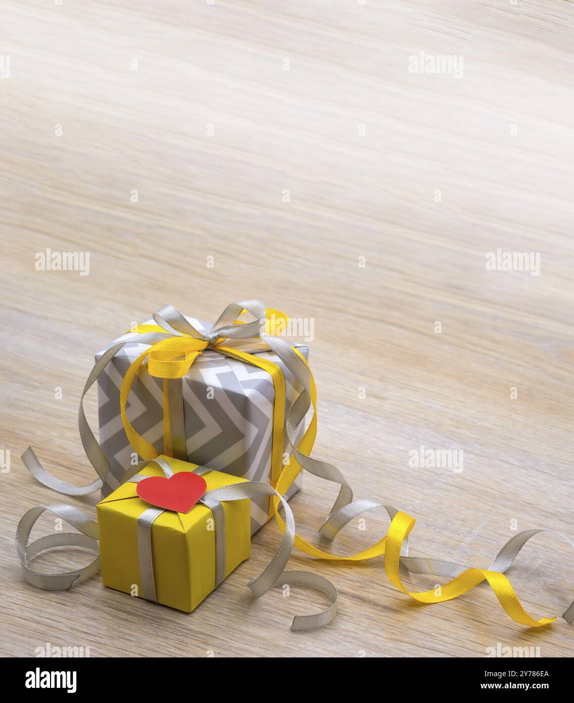 Décor pour la saint-valentin le 14 février. Cadeau gris avec ruban jaune. Couleur jaune-gris dans les cadeaux. Emballage cadeau avec coeurs Banque D'Images