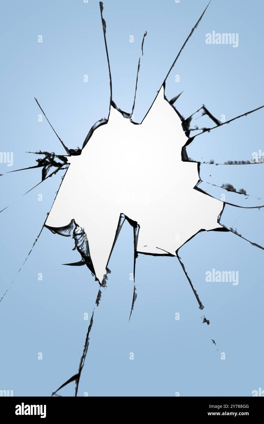 Morceaux de verre fissuré avec un trou au centre sur un fond bleu. Texture des fissures, l'effet de la destruction de la fenêtre Banque D'Images