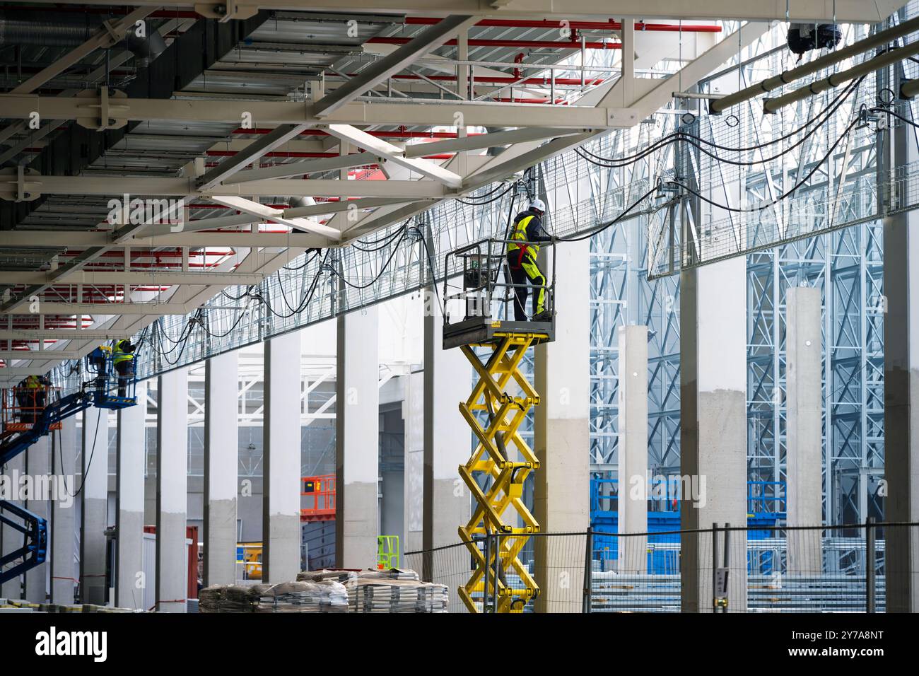 Électriciens installant des câbles sur des chemins de câbles travaillant en hauteur sur un chantier de construction Banque D'Images