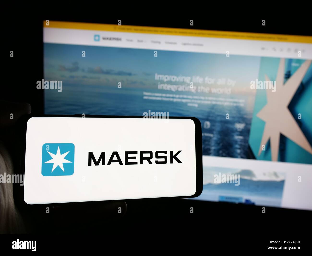 Personne tenant le smartphone avec le logo de la compagnie maritime danoise A.P. Moller - Maersk COMME sur l'écran en face du site Web. Concentrez-vous sur l'affichage du téléphone. Banque D'Images