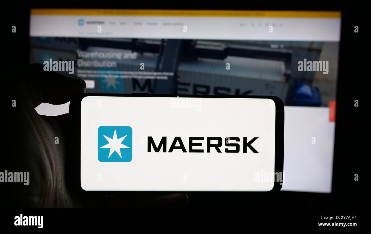 Personne tenant le téléphone portable avec le logo de la compagnie maritime danoise AP Moller - Maersk COMME sur l'écran en face de la page Web. Concentrez-vous sur l'affichage du téléphone. Banque D'Images