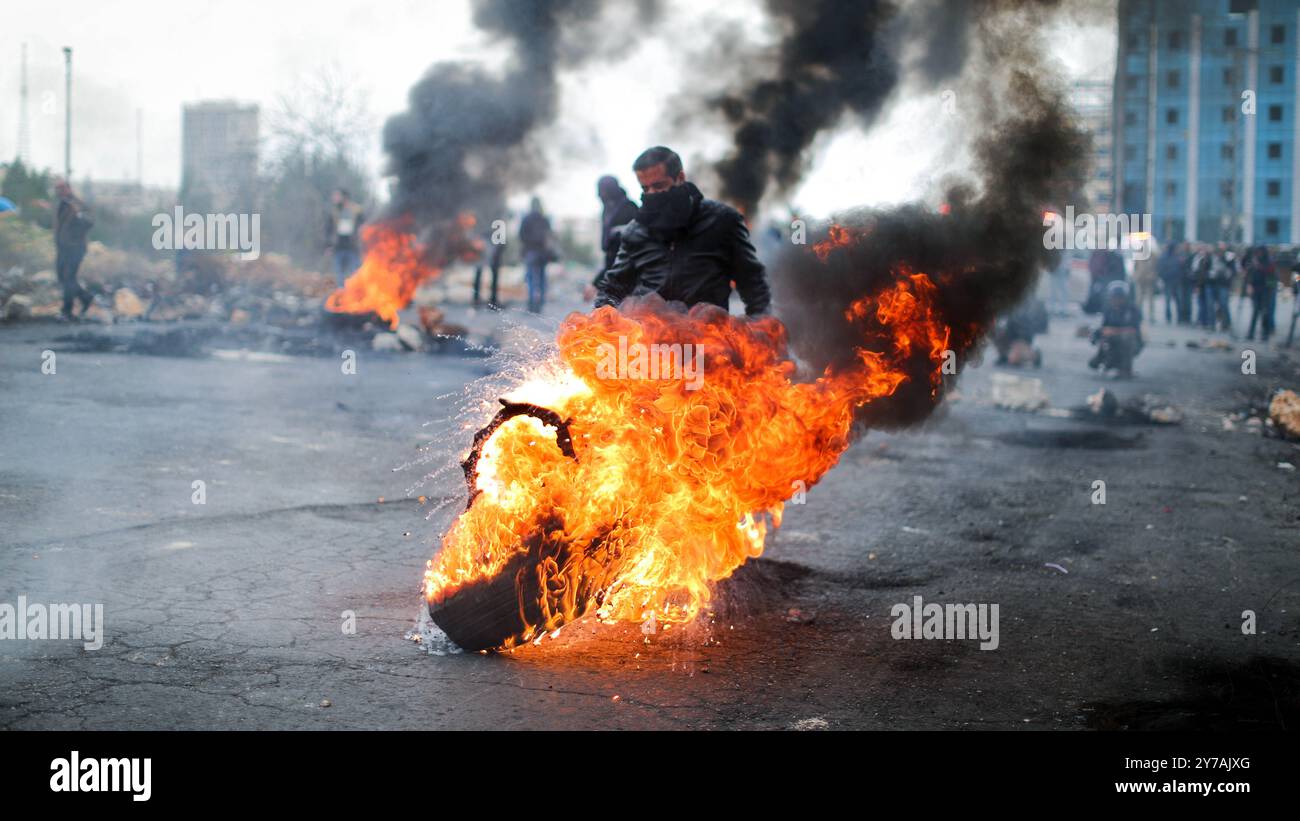 Des lanceurs de pierres palestiniens brûlent des pneus lors d'affrontements avec les forces de sécurité israéliennes à la suite des prières hebdomadaires musulmanes du vendredi dans la ville de Ramallah, en Cisjordanie. Des affrontements ont éclaté alors que des manifestations en cours ont eu lieu contre l'annonce faite par le président américain Trump le 6 décembre qu'il reconnaissait Jérusalem comme capitale d'Israël et qu'il déplacerait l'ambassade américaine de tel Aviv à Jérusalem. Décembre Banque D'Images