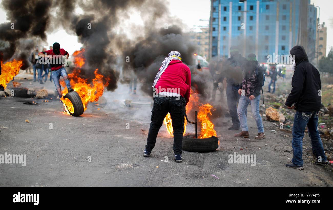 Des lanceurs de pierres palestiniens brûlent des pneus lors d'affrontements avec les forces de sécurité israéliennes à la suite des prières hebdomadaires musulmanes du vendredi dans la ville de Ramallah, en Cisjordanie. Des affrontements ont éclaté alors que des manifestations en cours ont eu lieu contre l'annonce faite par le président américain Trump le 6 décembre qu'il reconnaissait Jérusalem comme capitale d'Israël et qu'il déplacerait l'ambassade américaine de tel Aviv à Jérusalem. Décembre Banque D'Images