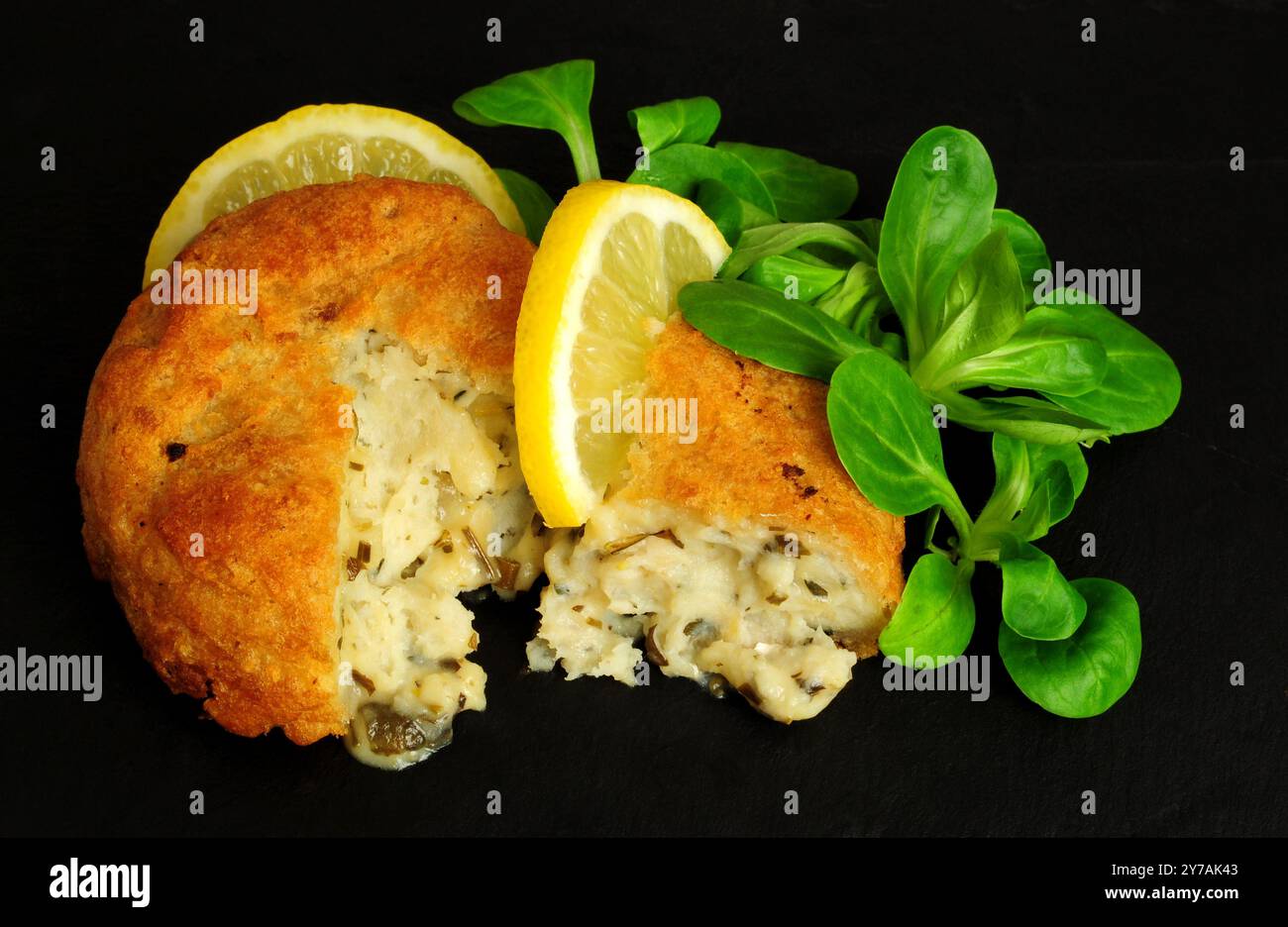 Gâteaux d'églefin et de pommes de terre panés avec garniture de laitue de feuilles de citron et d'agneau Banque D'Images