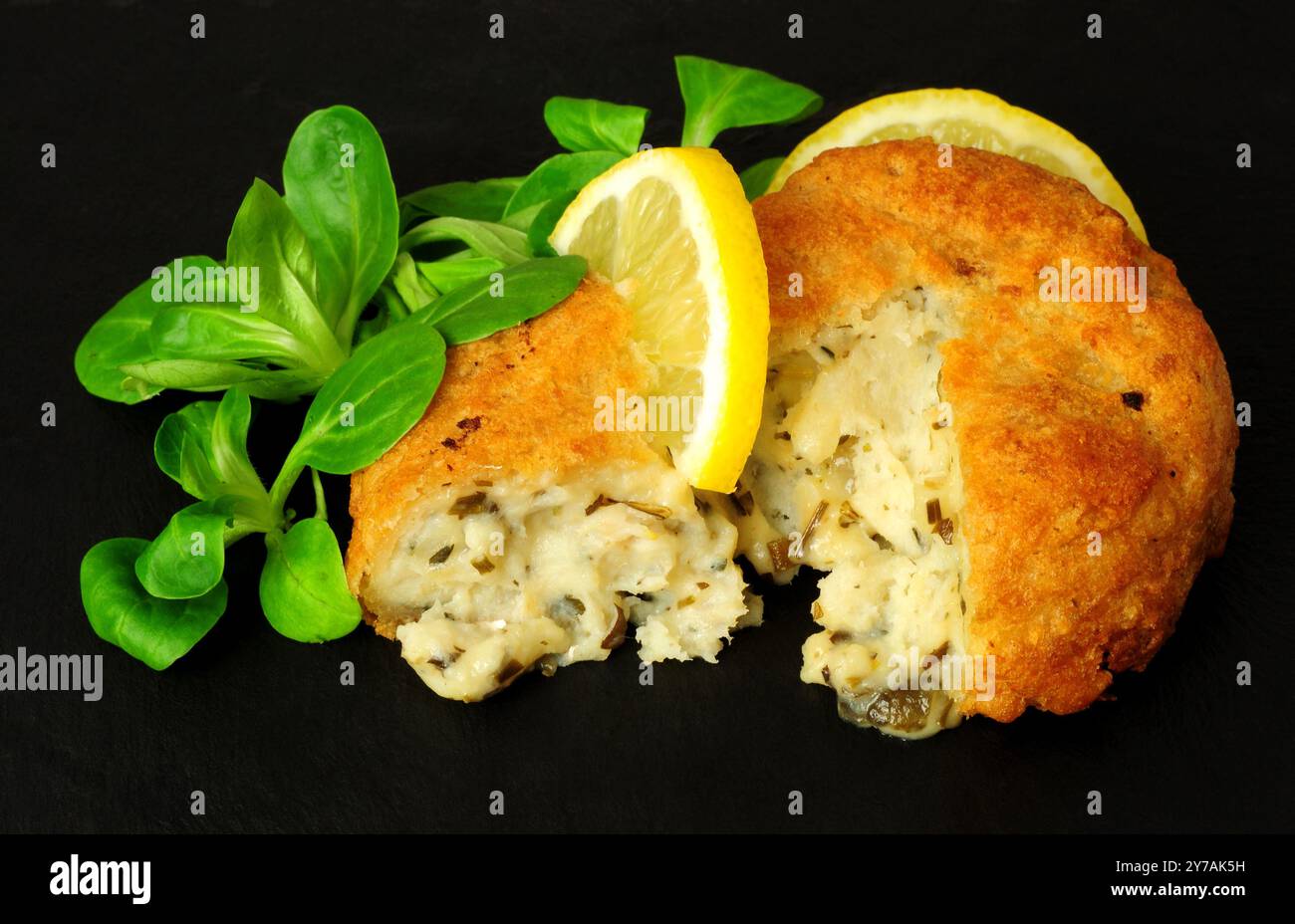 Gâteaux d'églefin et de pommes de terre panés avec garniture de laitue de feuilles de citron et d'agneau Banque D'Images