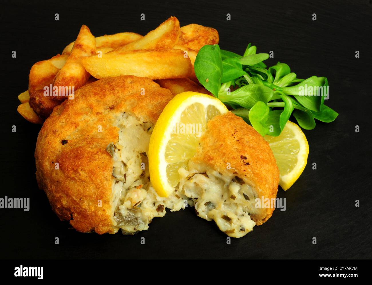 Gâteaux et frites de poisson d'églefin et de pommes de terre panés avec garniture de laitue de feuilles de citron et d'agneau Banque D'Images