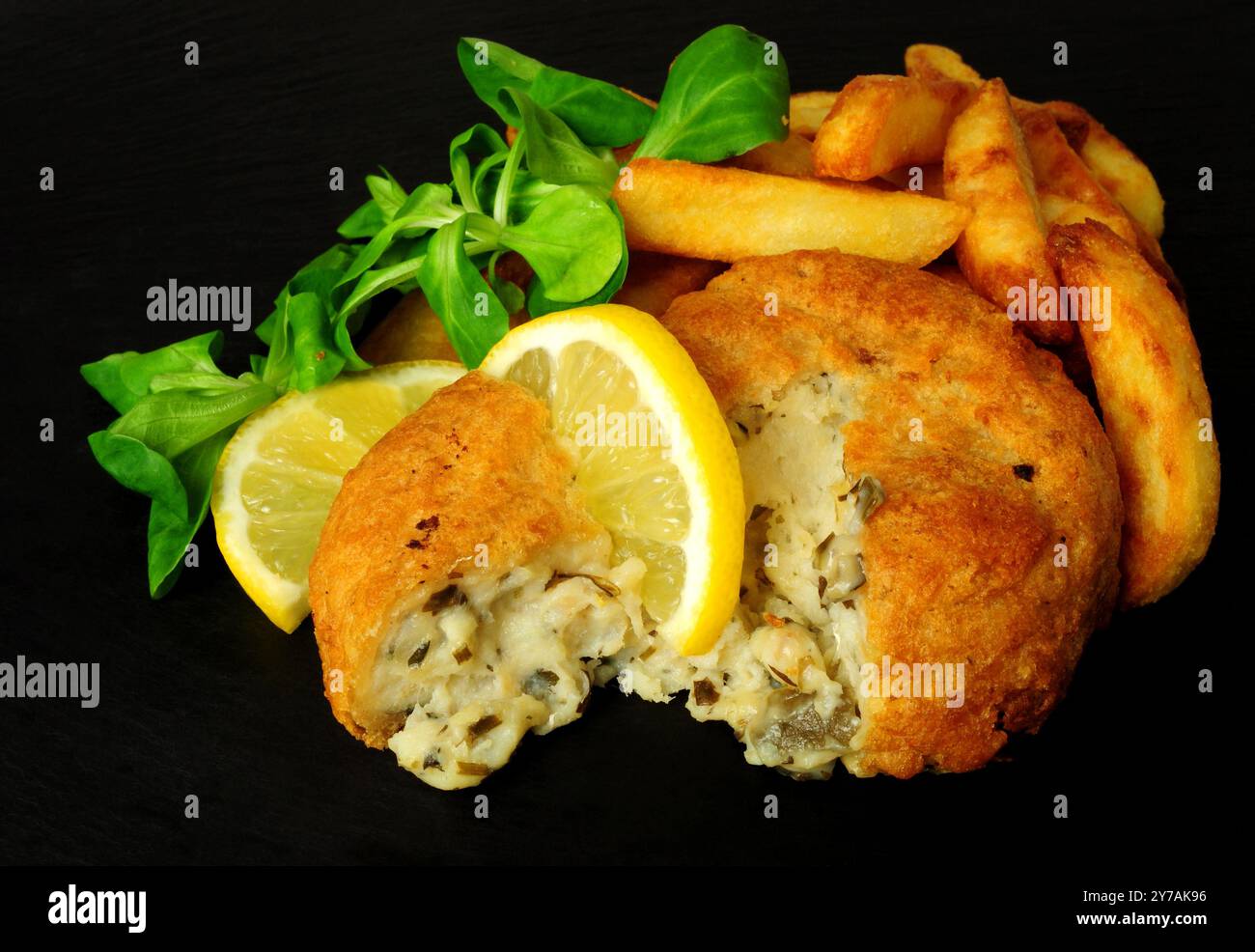 Gâteaux et frites de poisson d'églefin et de pommes de terre panés avec garniture de laitue de feuilles de citron et d'agneau Banque D'Images