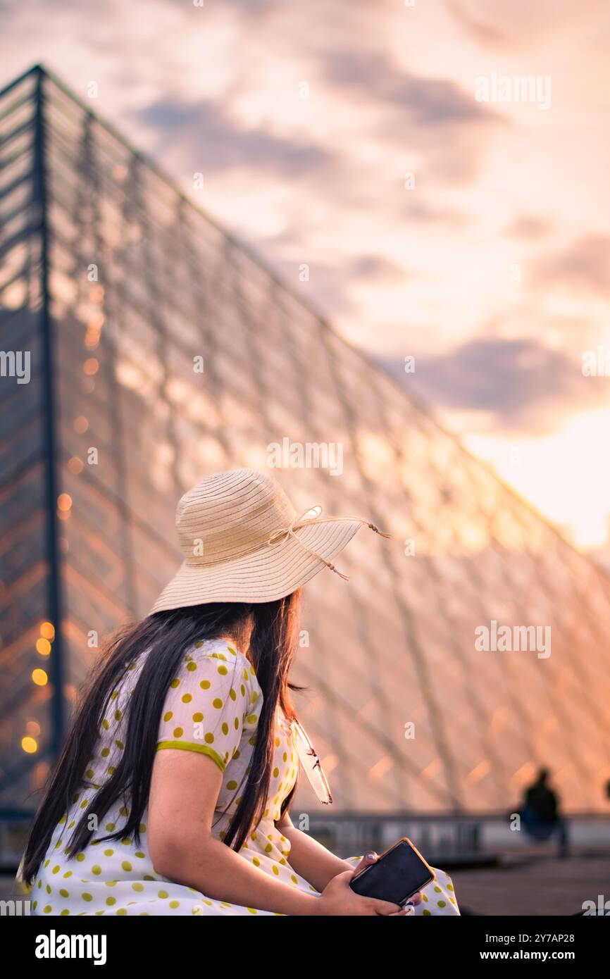 Une belle femme devant le musée du Louvre, l'un des plus grands musées du monde et un monument historique. Un point de repère central de Paris, France. Banque D'Images