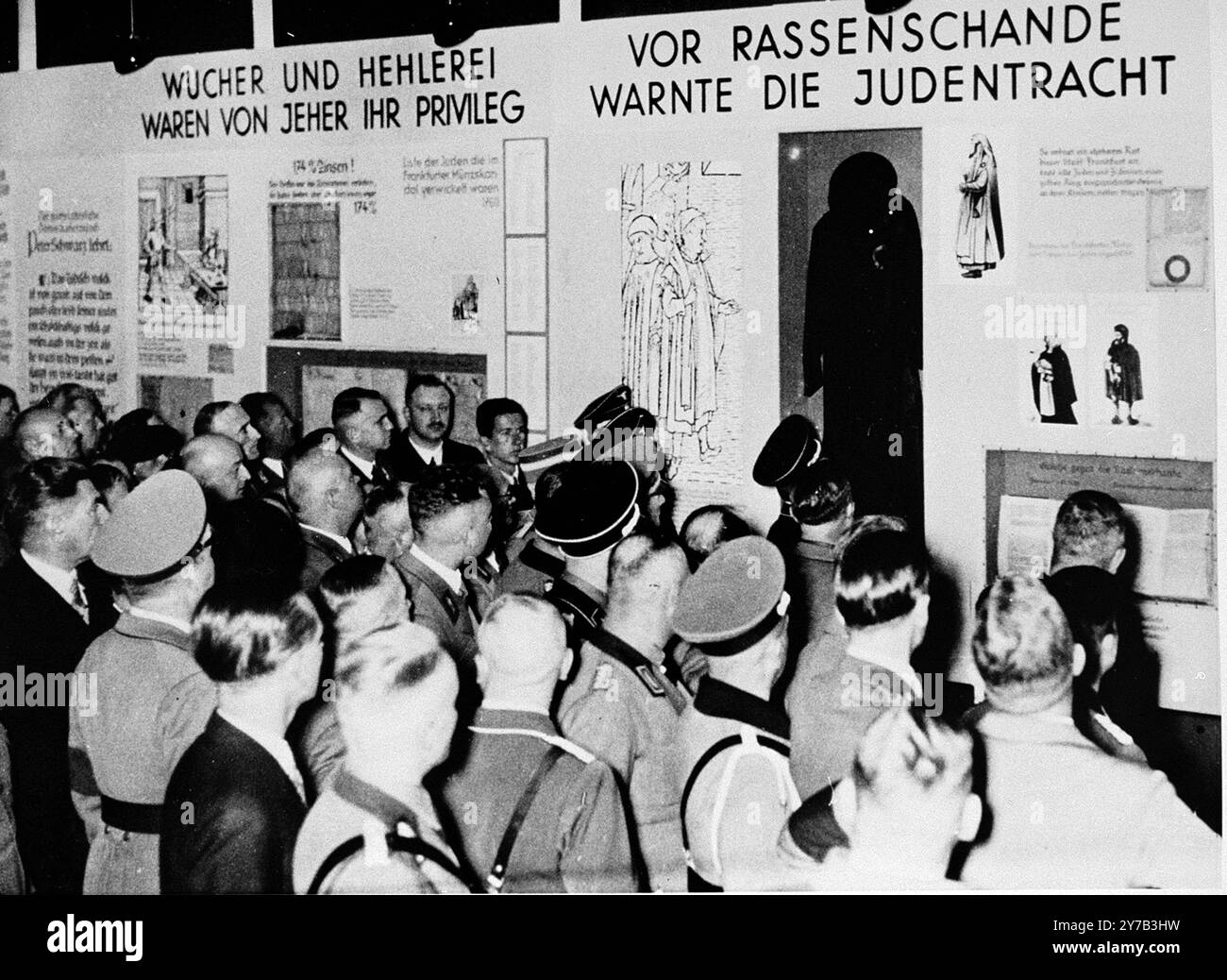 Les fonctionnaires nazis présents à l'ouverture de l'exposition « le juif éternel » à Munich, visionnent un segment intitulé « la robe juive était un avertissement contre la souillure raciale ». À gauche se trouve un segment intitulé : «L'usure et la clôture des marchandises ont toujours été leur privilège». La photo est datée du 8 novembre 1937 Banque D'Images
