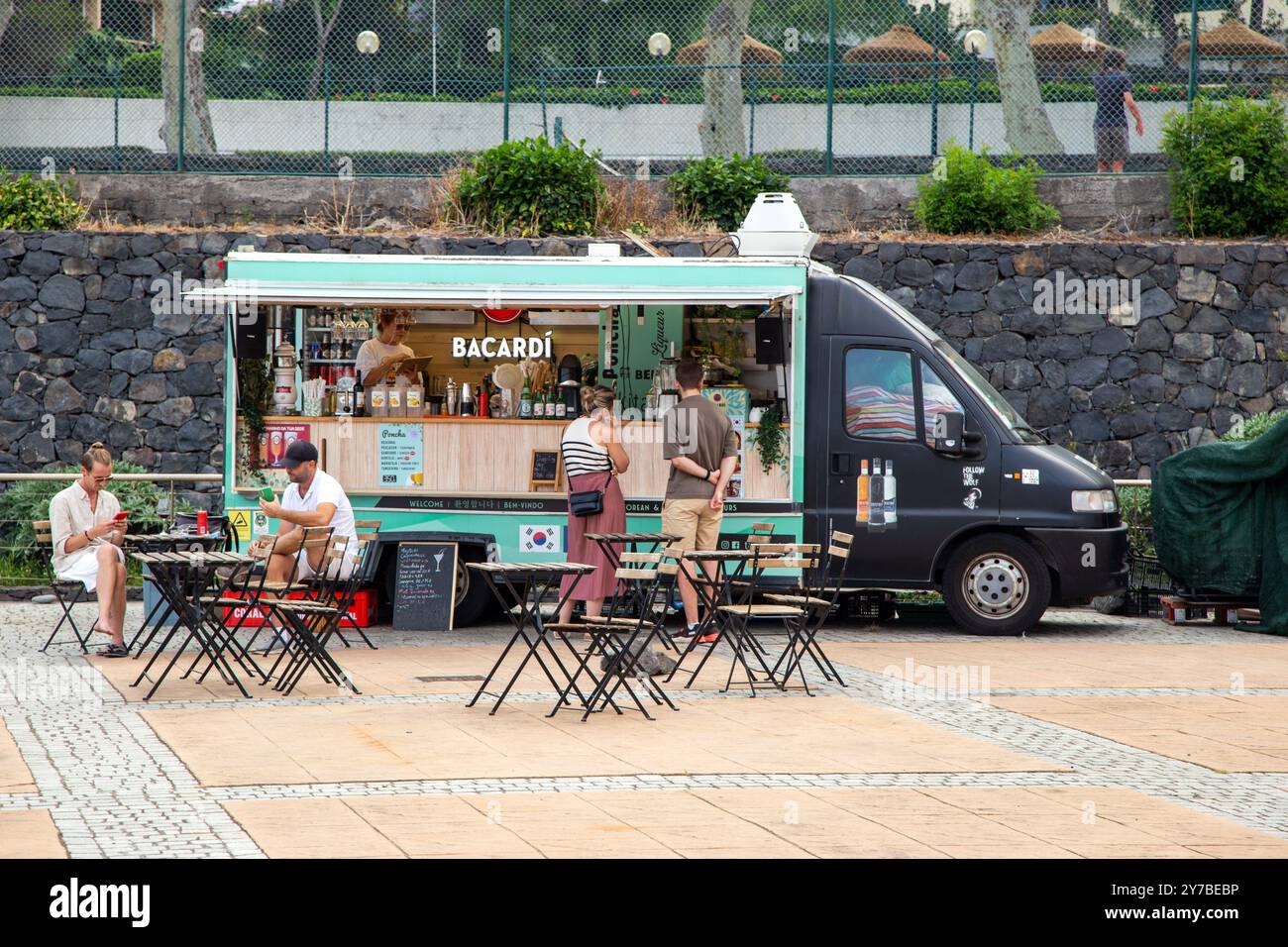 Les gens assis à boire dans un bar à cocktails mobile à la station balnéaire de Machico sur l'île portugaise de Madère Banque D'Images