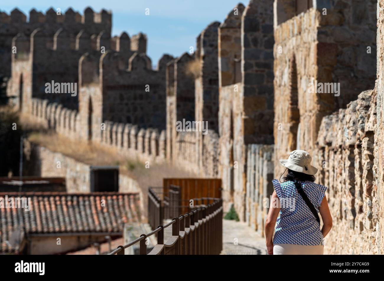 Femme avec chapeau marchant sur le mur entourant la vieille ville de la ville espagnole d'Avila (Espagne) par un matin d'été ensoleillé Banque D'Images