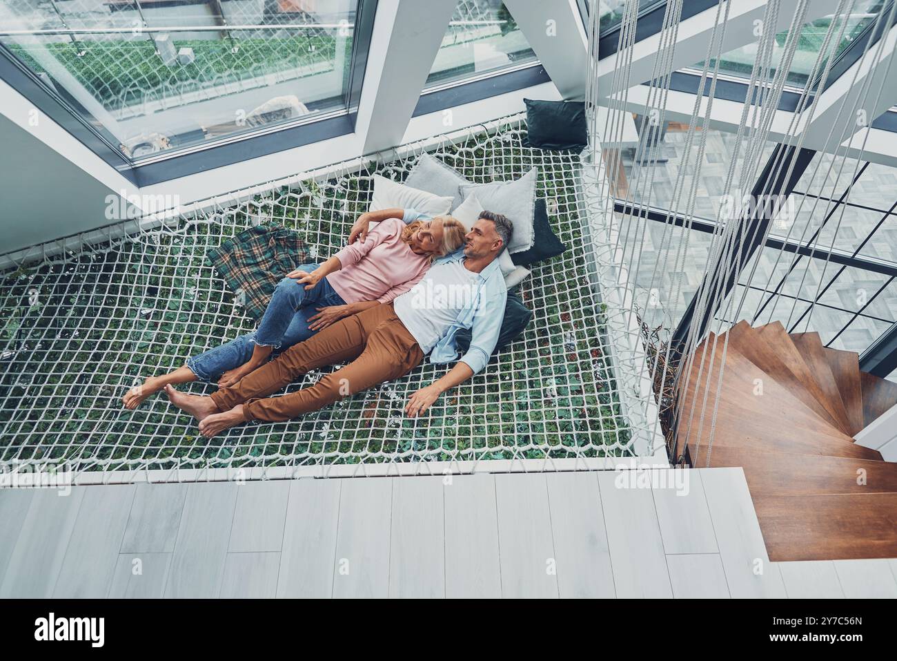 Vue de dessus de beau couple mature souriant et communiquant tout en se relaxant dans un grand hamac à la maison ensemble Banque D'Images