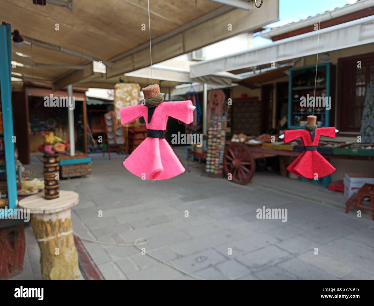 Des poupées colorées en tissu habillées dans une tenue derviche turque tourbillonnante traditionnelle sont suspendues à des cordes dans un étal de marché. Les poupées sont entourées de o Banque D'Images