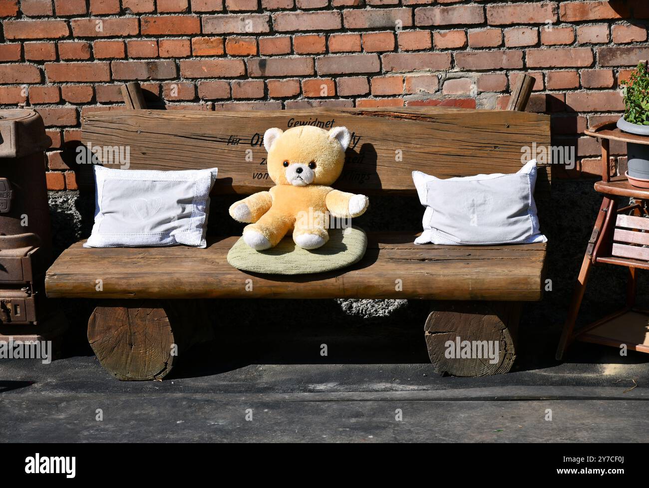 Un ours en peluche est assis sur un banc en bois Banque D'Images