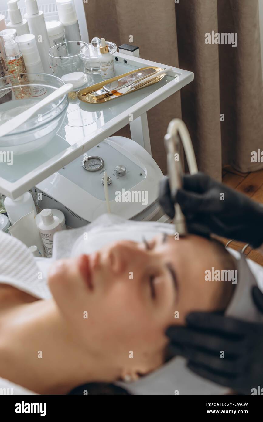 Dermatologue professionnel dans les gants médicaux effectue la microdermabrasion sur la femme dans un salon de beauté Banque D'Images