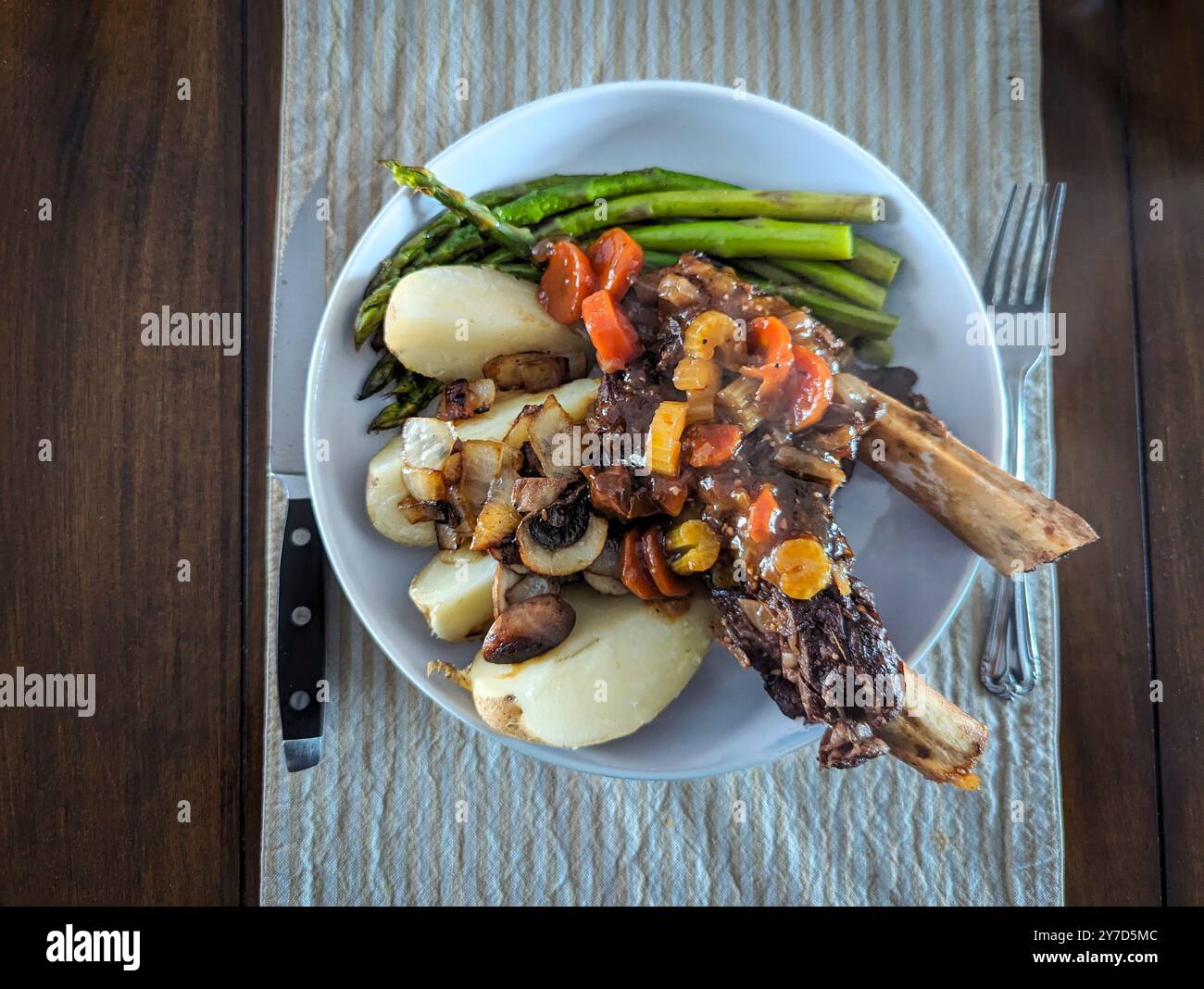 Côtes de bœuf braisées gourmandes aux asperges et aux pommes de terre servies sur un plat blanc Banque D'Images