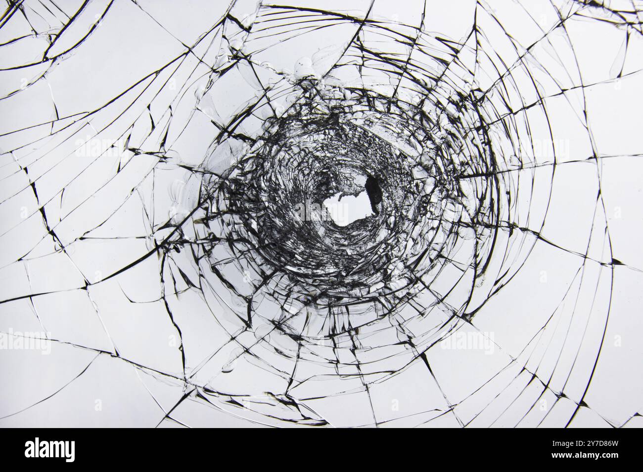 Un trou et des fissures dans le verre brisé sur une fenêtre de verre de voiture de pare-brise. Pare-brise transparent d'une voiture avec un trou après les tirs Banque D'Images