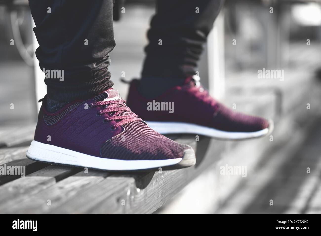 Un homme en baskets marche dans la rue par une journée ensoleillée Banque D'Images