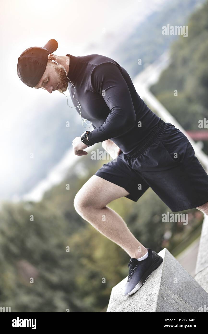 Athlète barbu musclé vérifiant les calories brûlées sur la montre intelligente après une bonne séance d'entraînement sur le parc de la ville Banque D'Images