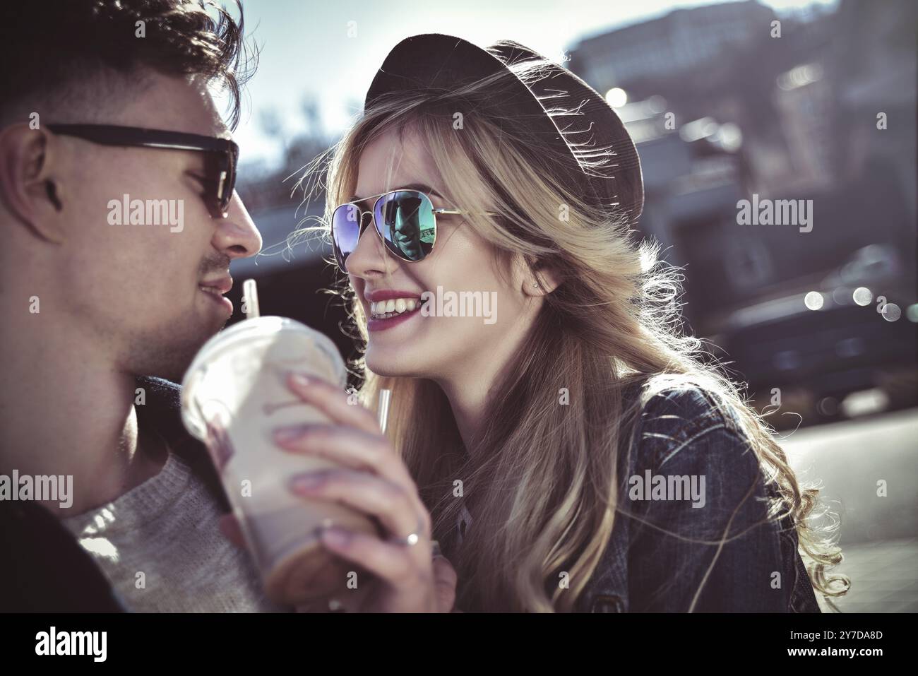 Un couple souriant se promène dans la rue le week-end et boit quelques cocktails Banque D'Images