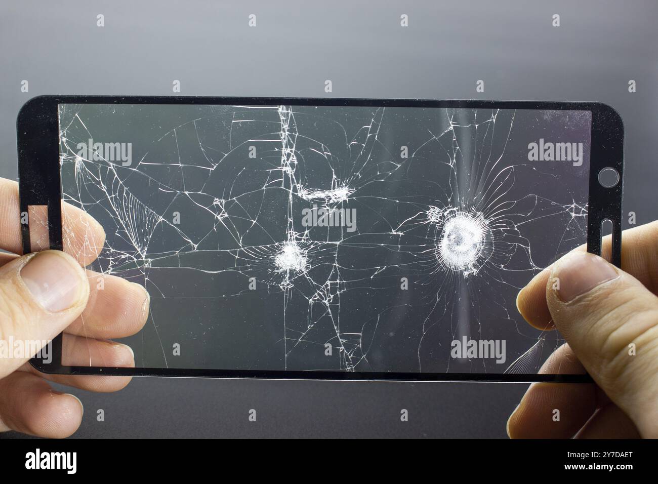 Verre de protection cassé du smartphone avec des mains fissurées sur fond noir. Verre de protection endommagé, photo lors du remplacement de la protection d'écran, cellule Banque D'Images