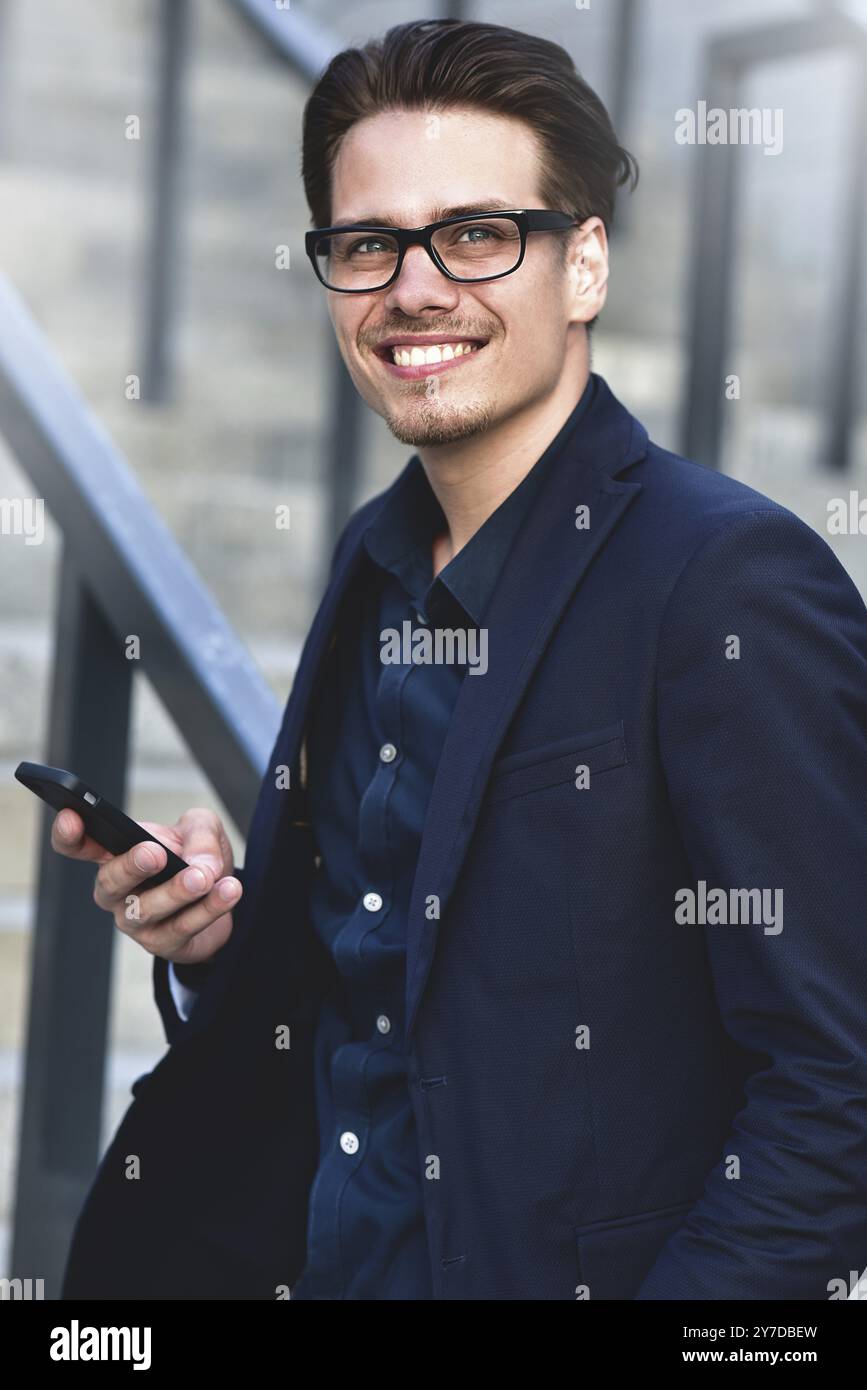 Heureux homme d'affaires caucasien dans des lunettes habillé à l'usure classique debout dans la rue Banque D'Images