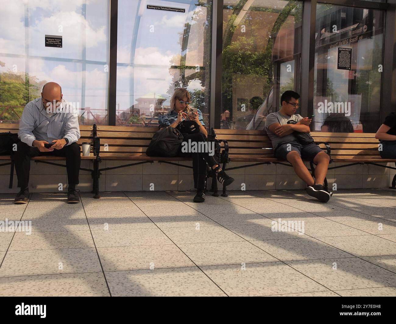 Des étrangers se sont infiltrés dans leurs téléphones à la gare du Summit, New Jersey, alors qu'ils ignoraient les environs. Banque D'Images