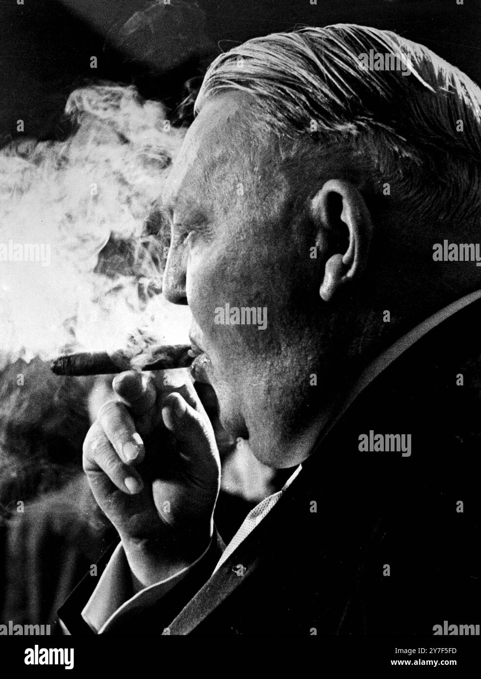 Le vice-chancelier ouest-allemand Ludwig Erhard semble monter un écran de fumée de son cigare alors qu'il parle aux journaux après une conférence de 90 minutes avec le président Kennedy à la Maison Blanche. Erhard a déclaré que lui et le président avaient une discussion générale sur les problèmes mondiaux. Il a déclaré aux journalistes qu'une proposition de l'Union soviétique pour des pourparlers bilatéraux sur le problème de Berlin Allemagne était un mouvement de propoganda avec peu de réalité politique 10 janvier 1962 Banque D'Images