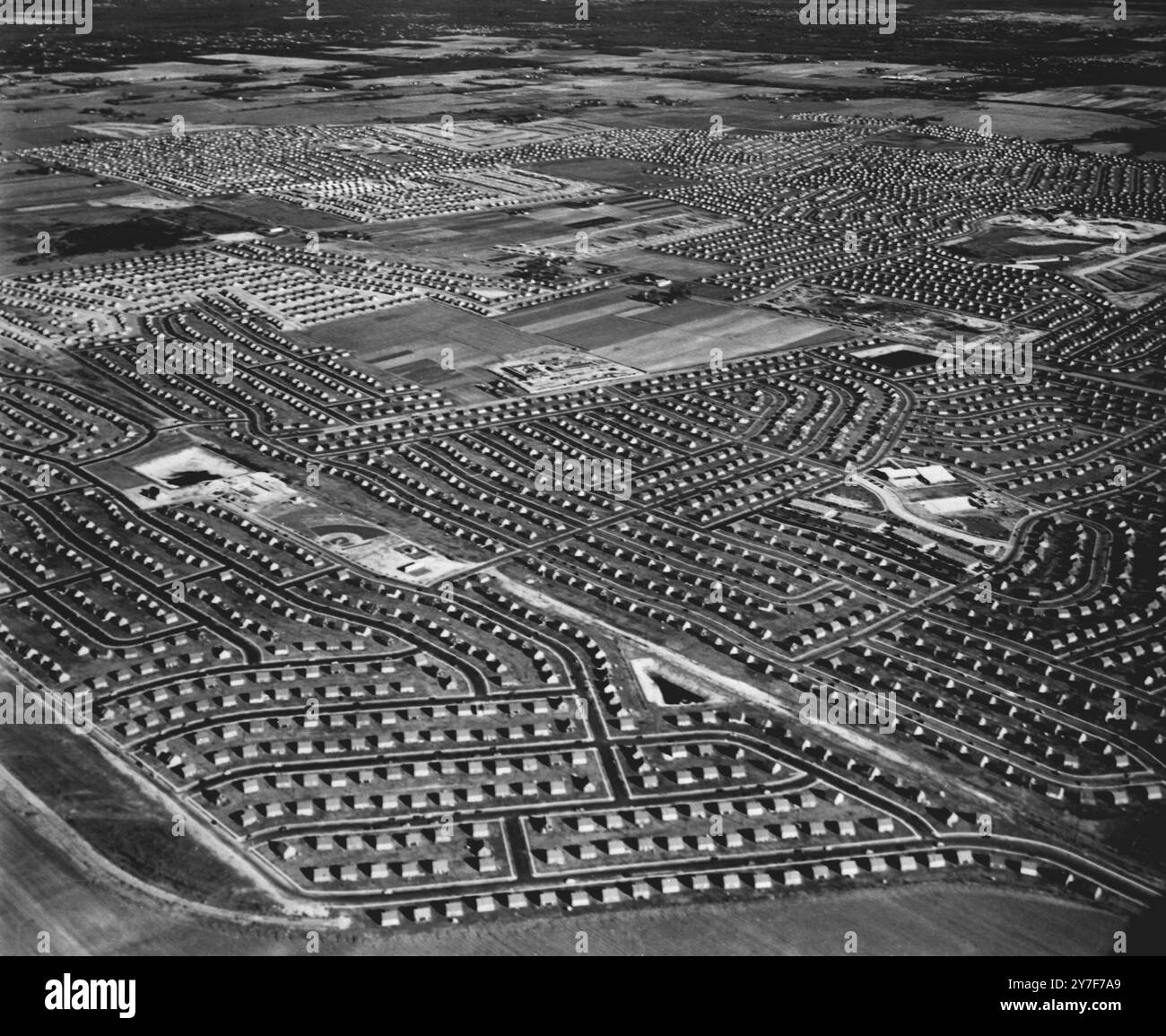 Levittown, USA un développement industrialisé pour les vétérans de la guerre américaine. Ces maisons bien construites et bon marché, toutes exactement pareilles, posées dans toute leur boîte terne, comme des voitures garées, ont produit une peur irraisonnée que les logements industrialisés doivent être horribles. Certaines parties de la ville sont encore non construites, et au centre, on peut voir l'un des centres commerciaux. Vers la gauche, un losange de baseball est visible. 1949 Banque D'Images