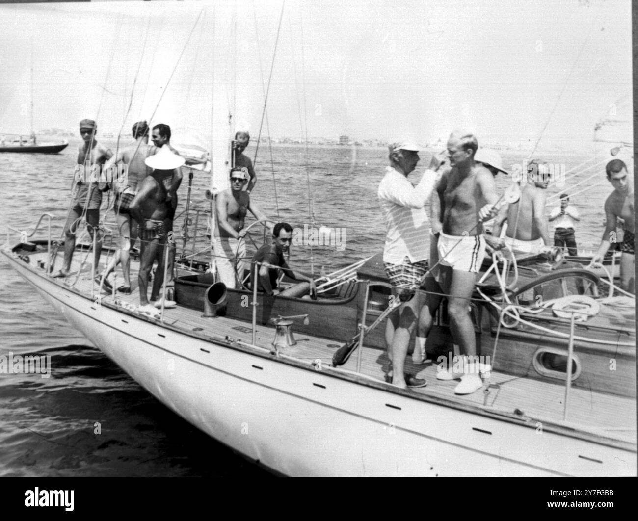 King Constantine (pantalon blanc, à gauche) à la barre du yacht 'Ivanhoe' pendant la course de yachting de 90 miles sous les règles du Royal Ocean Racing Club. Derrière le roi se trouve le prince Karl de Hesse, le prince Vittorio Emanuel d'Italie, à gauche tournant le dos. Le prince Richard de Sayn Wittgenstein Berleburg est sur la droite discutant avec M. Goulandris, l'armateur grec, et propriétaire du yacht. L'extrême droite est Don Juan Carlos des Asturies ( lunettes noires ) 21 août 1963 - Corfou Grèce Banque D'Images