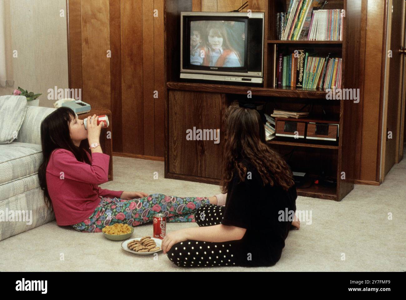 des amis de 11 ans mangeant de la malbouffe et regardant une vidéo à la télévision Banque D'Images des amis de 11 ans mangeant de la malbouffe et regardant une vidéo à la télévision Banque D'Images