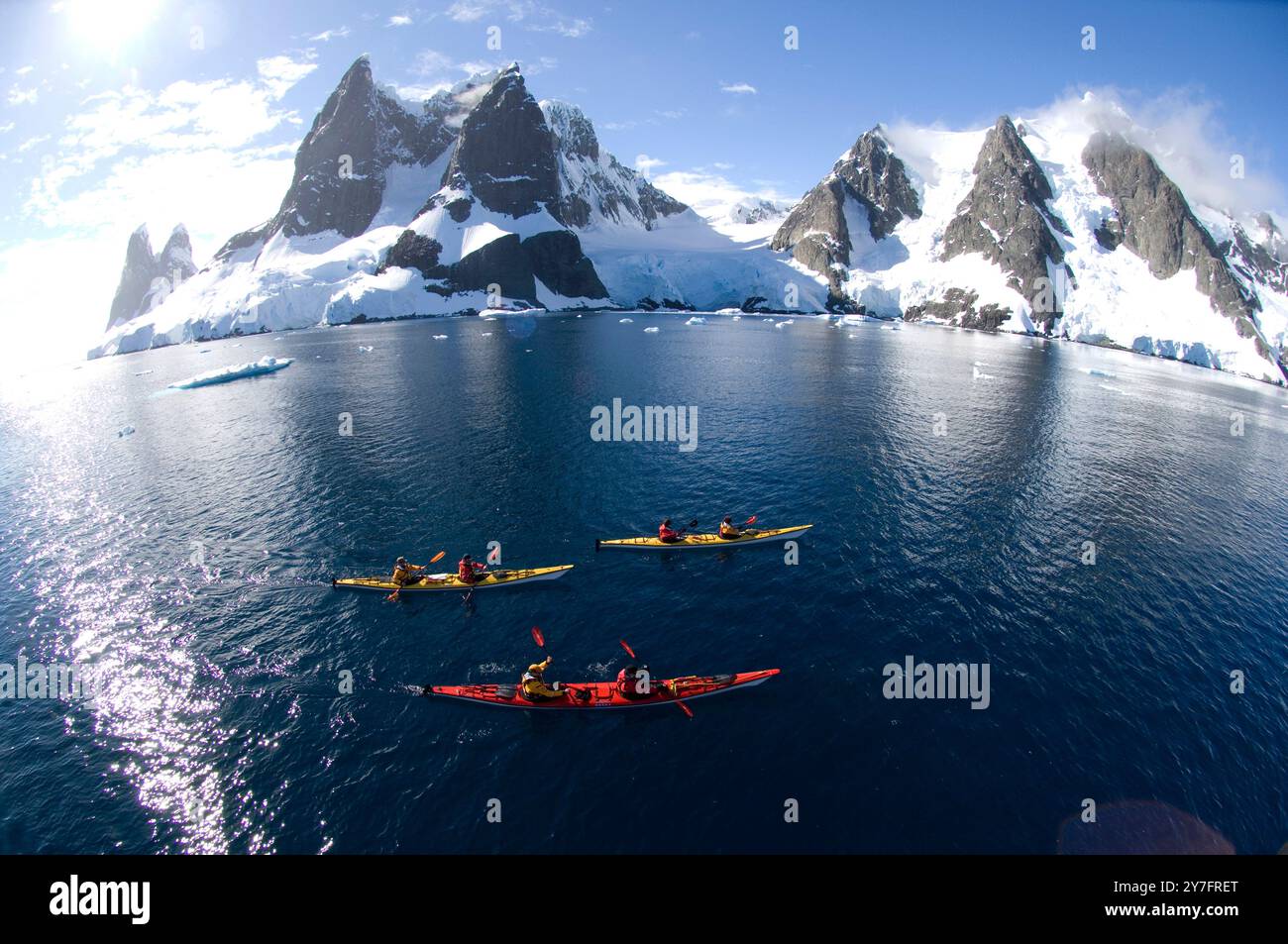 Les kayakistes pagayent dans l'eau bleue claire du canal Lemaire sur la côte ouest de la péninsule de l'Antarctique connue sous le nom de Graham Banque D'Images