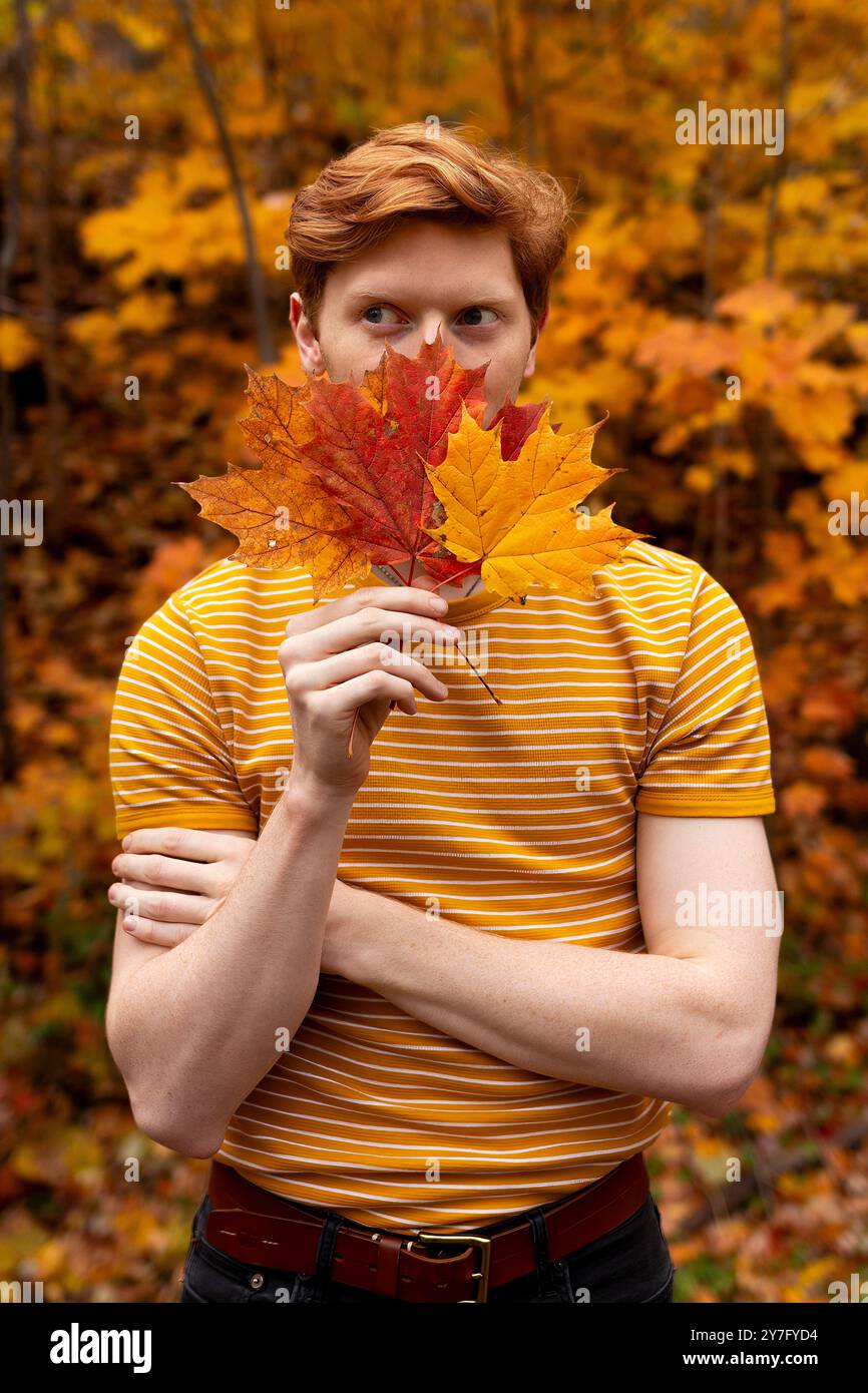 homme aux cheveux roux dans une forêt remplie de feuilles d'automne colorées Banque D'Images